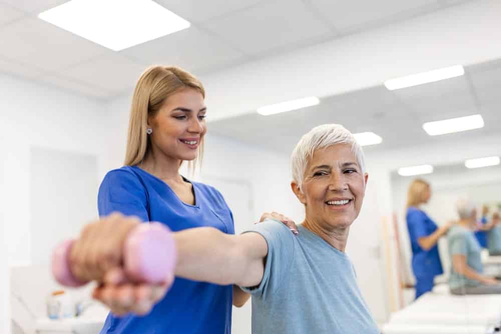 Woman assisting elderly with exercise