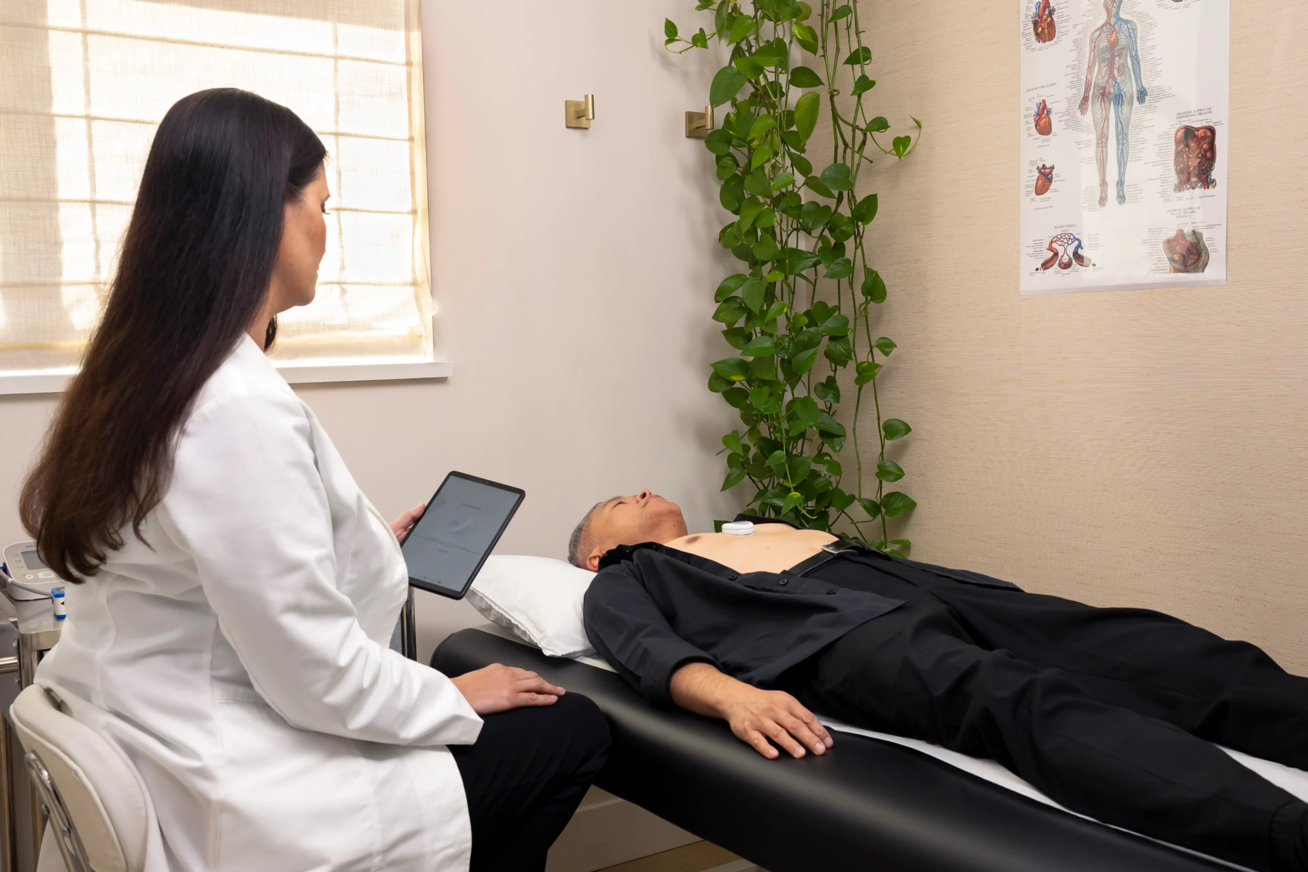 Healthcare professional monitoring a CardioClin test on a tablet while the patient lies down