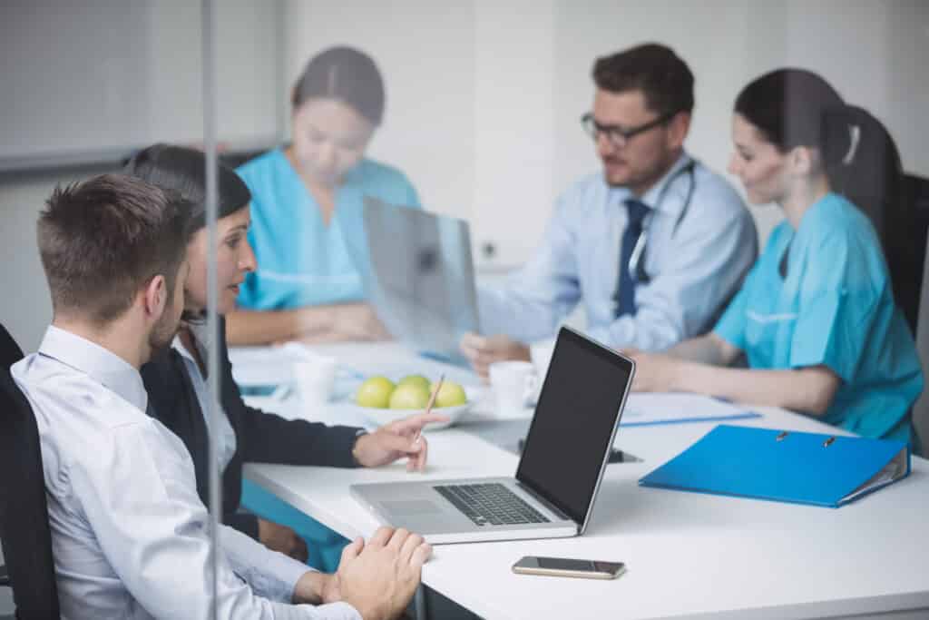 Doctors discussing patient data over laptop in meeting at conference room